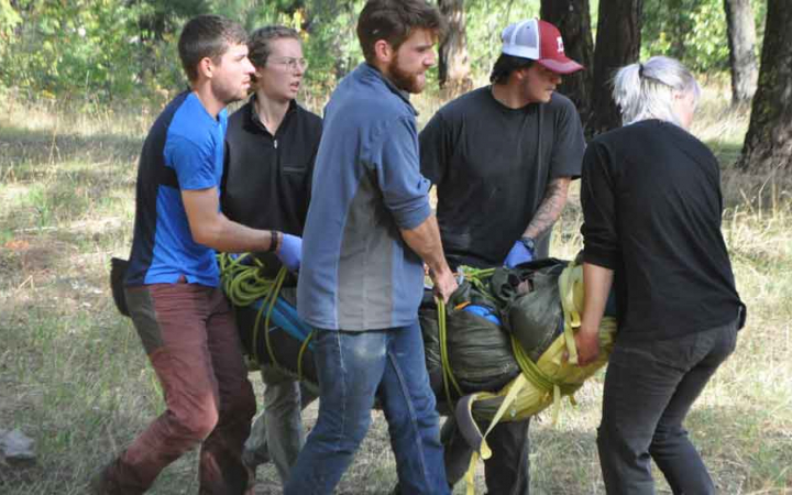 a group of students carry a person during a wilderness first aid training 